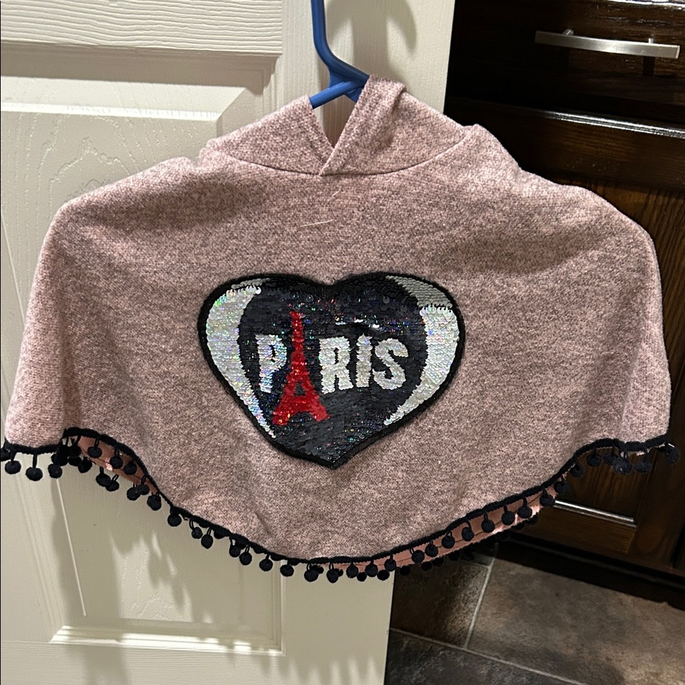 Pink ‘Paris sequins’ poncho with ball tassels.